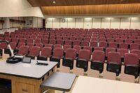 Back of room view of student auditorium seating and exit door at rear of room