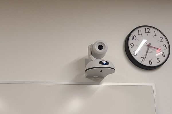 Camera mounted to a wall and instructor enabled adjustments to the lens to allow the instructor to be "seen" by the camera in more locations around the room