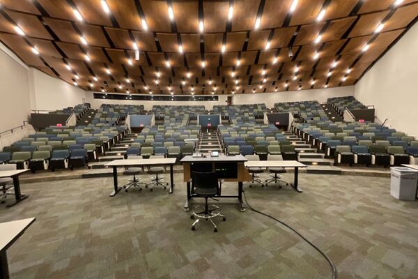 Back of room view of student auditorium seating and three exits at rear of room