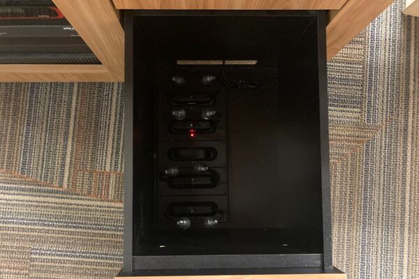 Pedestal - inside view of drawer showing assistive listening devices in charging base