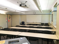 Photo of back of room from front of room with a whiteboard and clock on back wall.