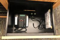 Pedestal - inside view of drawer showing two wireless mics in charging base and telephone