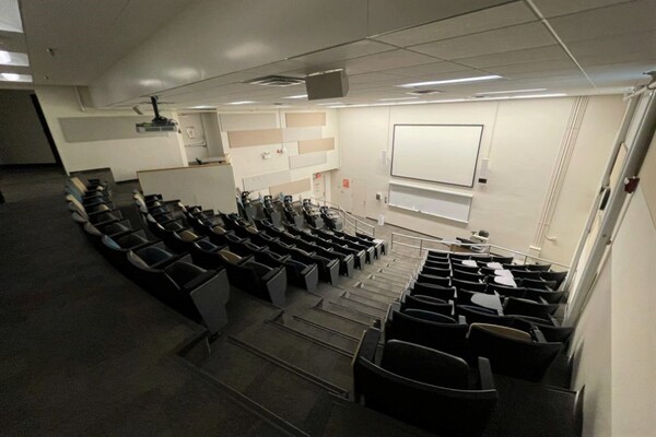 Front of room view with lectern on right in front of markerboard and projection screen above