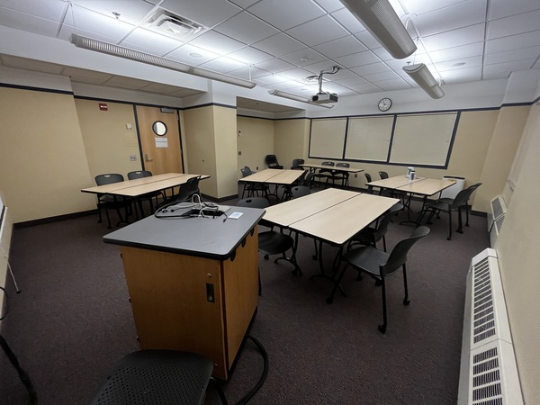 Photo of back of room from front of room with tables set up for groups of 4.