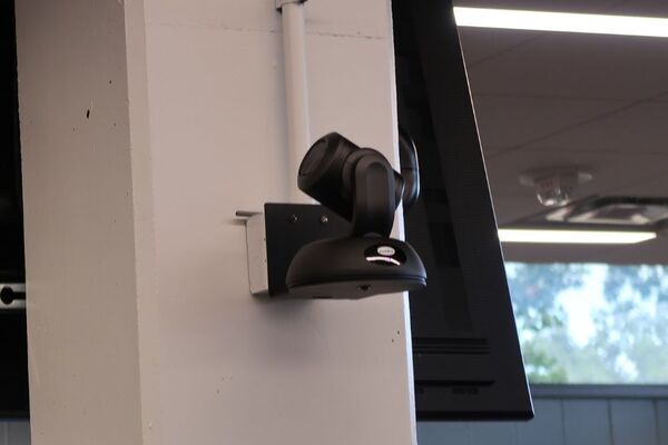 Camera mounted to a wall and instructor enabled adjustments to the lens to allow the instructor to be "seen" by the camera in more locations around the room