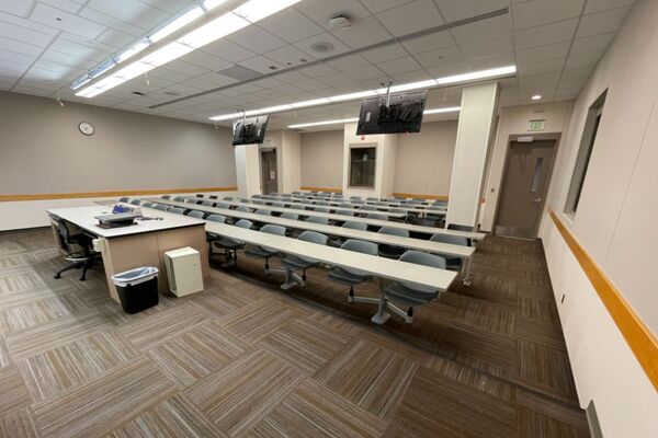 Back of room view of student fixed table and chair seating and exit doors at rear of room