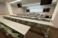 Front of room view with lectern center in front of markerboard and display screens to left and right