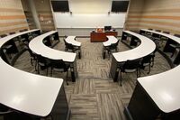 Front of room view with lectern on center in front of markerboard and display screen on the upper left and right