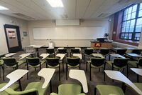 Front of room view with lectern on right in front of markerboard and projection screen partially raised