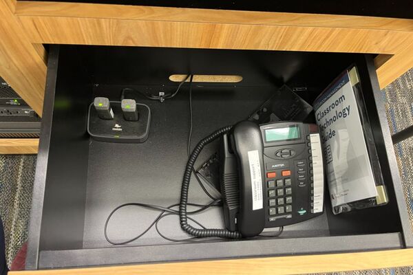 Pedestal - inside view of drawer showing two wireless mics in charging base and telephone