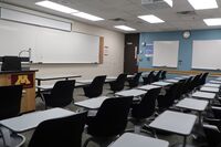 Front of room view with lectern on left in front of markerboard, exit door on right