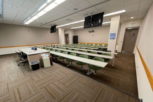 Back of room view of student fixed table and chair seating and exit doors at rear of room