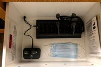 Pedestal - inside view of drawer showing two wireless mics in charging base and assistive listening devices in charger