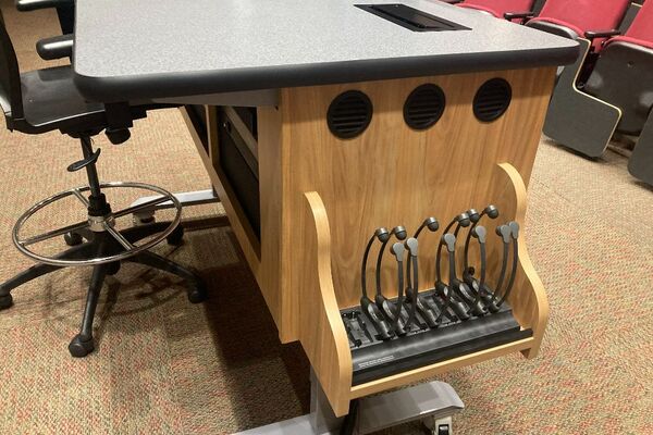 Pedestal - inside view of drawer showing two wireless mics in charging base and assistive listening devices in charger