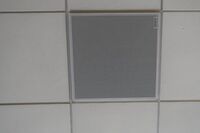 White 2x 2 tile mounted in the ceiling to provide microphone coverage over student seating