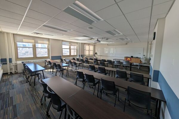 Front of room view with lectern on right in front of markerboard, exit door on right wall