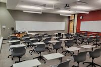 Front of room view with lectern on left in front of markerboard and exit door on the right