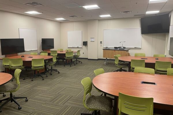 View with lectern center in front of markerboard and student table display screens to left and right 