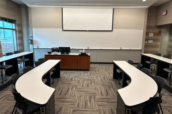 Front of room view with lectern on left in front of markerboard  with exit door to the right