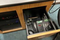 Pedestal - inside view of drawer showing two wireless mics in charging base and telephone