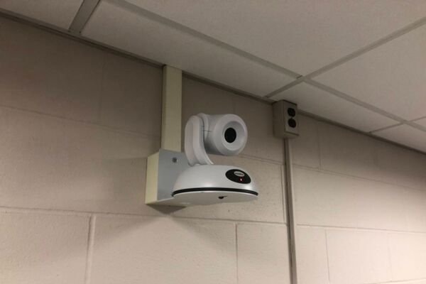 Camera mounted to a wall and instructor enabled adjustments to the lens to allow the instructor to be "seen" by the camera in more locations around the room