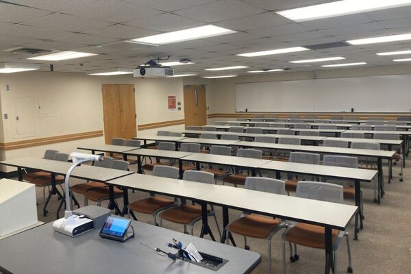 Front of room view with lectern on left in front of markerboard and exit door front right