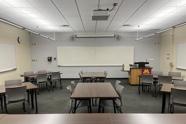 Front of room view with lectern on right in front of markerboard and projection screen partially raised