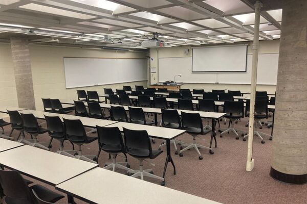 Front of room view with lectern on left in front of markerboard and projection screen partially raised