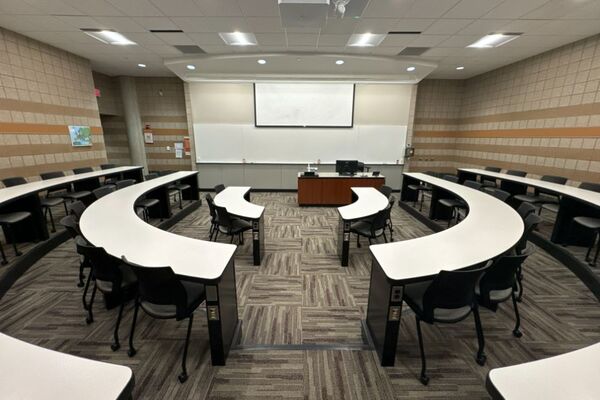 Front of room view with lectern center in front of markerboard, screen partially lowered