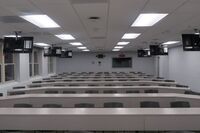 Back of room view of student table and chair seating and exit door at right rear of room