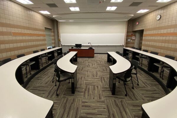 Front of room view with lectern center in front of markerboard with exit door at front right