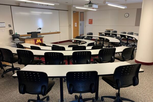 Front of room view with lectern on left in front of markerboard and exit door on the right