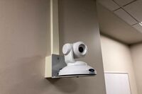 Camera mounted to a wall and instructor enabled adjustments to the lens to allow the instructor to be "seen" by the camera in more locations around the room