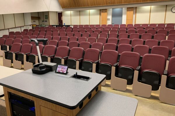 Back of room view of student auditorium seating and exit door at left rear of room