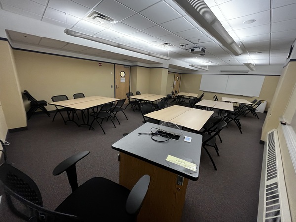 Photo of back of room from front of room with tables set for groups of 4.