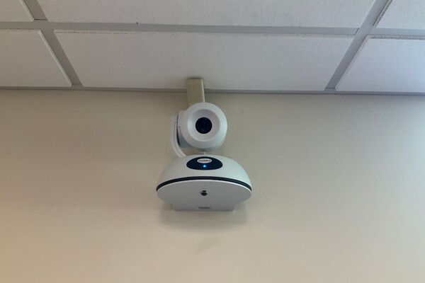 Camera mounted to a wall and instructor enabled adjustments to the lens to allow the instructor to be "seen" by the camera in more locations around the room