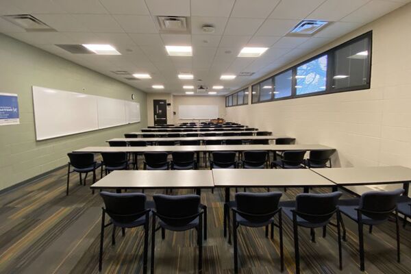 Front of room view with lectern on right in front of markerboard and exit door on left