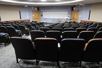 Front of room view with lectern on right in front of markerboard and exit doors to left and right