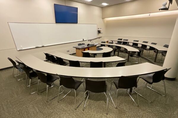 Front of room view with lectern centered in front of markerboard and display monitors above