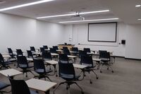 Front of room view with lectern on left side and projection screen fully lowered