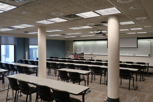 Front of room view with lectern on left in front of markerboard and projection screen partially raised