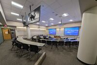 Front of room view with lectern center in front of markerboard and projection screens on left and right lowered