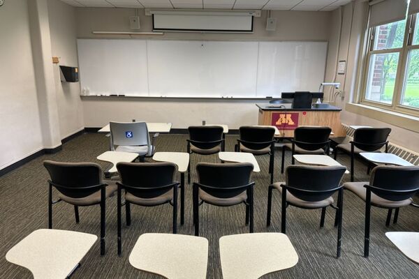 Front of room view with lectern on right side and projection screen partially lowered