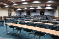 Back of room view of student tiered fixed table and chair seating and double exit doors at rear of room