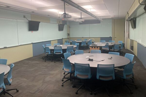 View of room with lectern center in front of markerboard and display monitors to left and right