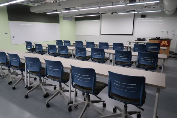 Front of room view with lectern on right in front of markerboard and projection screen raised