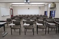 Back of room view of student tablet arm seating an exit door at rear left of room