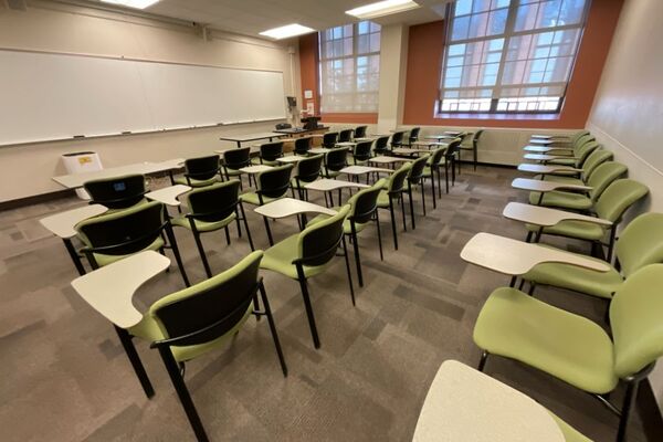 Front of room view with lectern on right in front of markerboard and projection screen partially raised