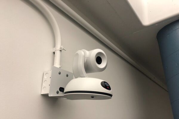 Camera mounted to a wall and instructor enabled adjustments to the lens to allow the instructor to be "seen" by the camera in more locations around the room