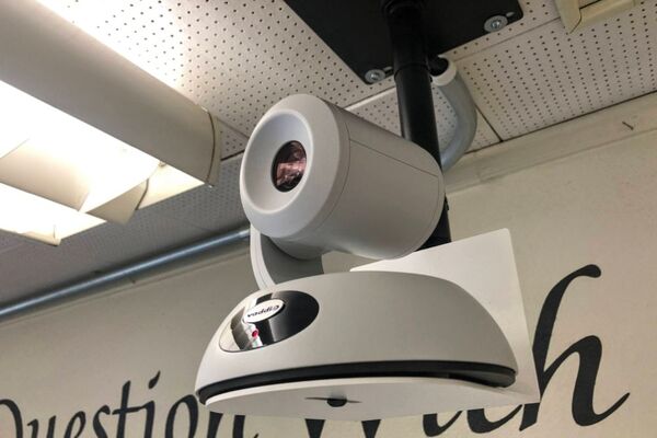 Camera mounted to a wall and instructor enabled adjustments to the lens to allow the instructor to be "seen" by the camera in more locations around the room